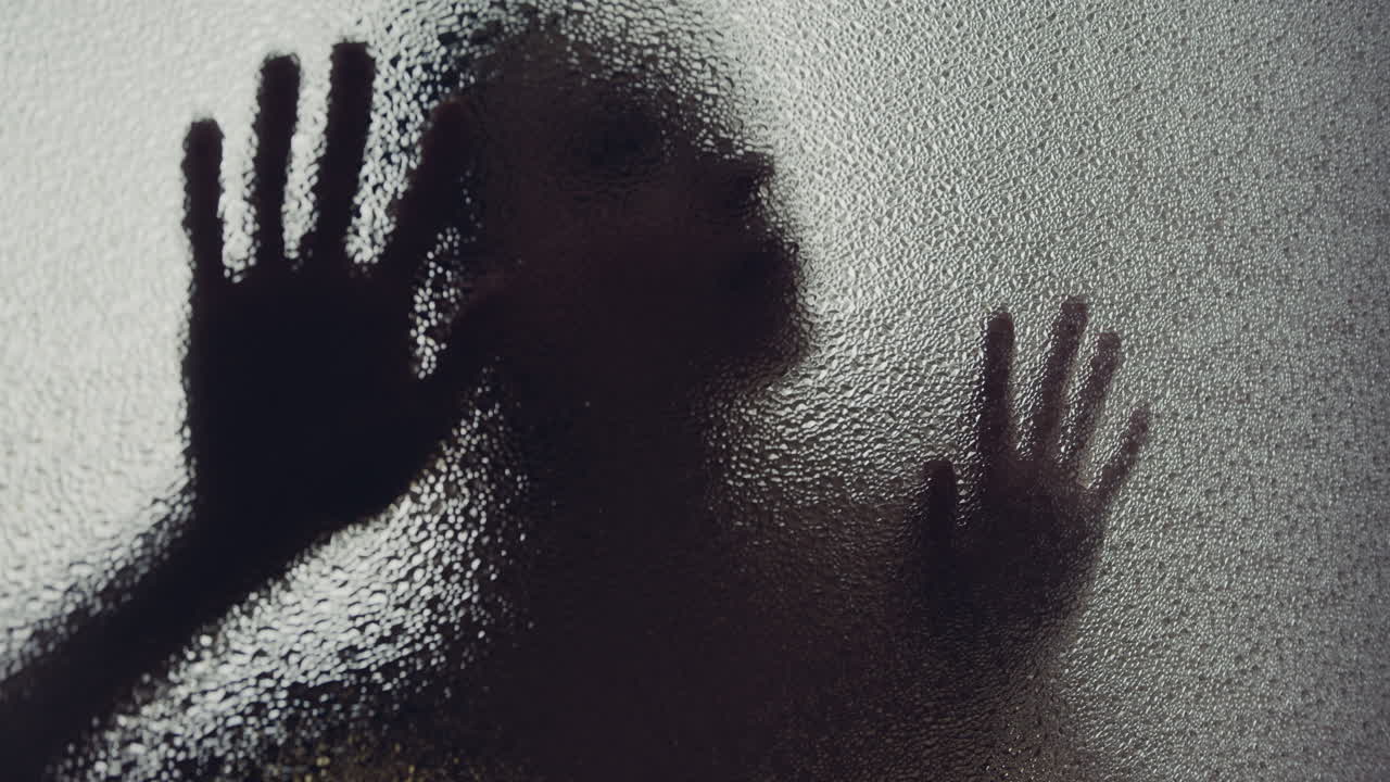 A female silhouette behind the frosted glass moves slowly
