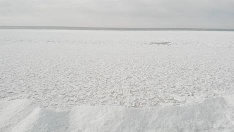 Drohnenaufnahmen,-Die-Im-Winter-über-Eisberge-Und-Gefrorene-Teile-Eines-Großen-Sees-Fliegen