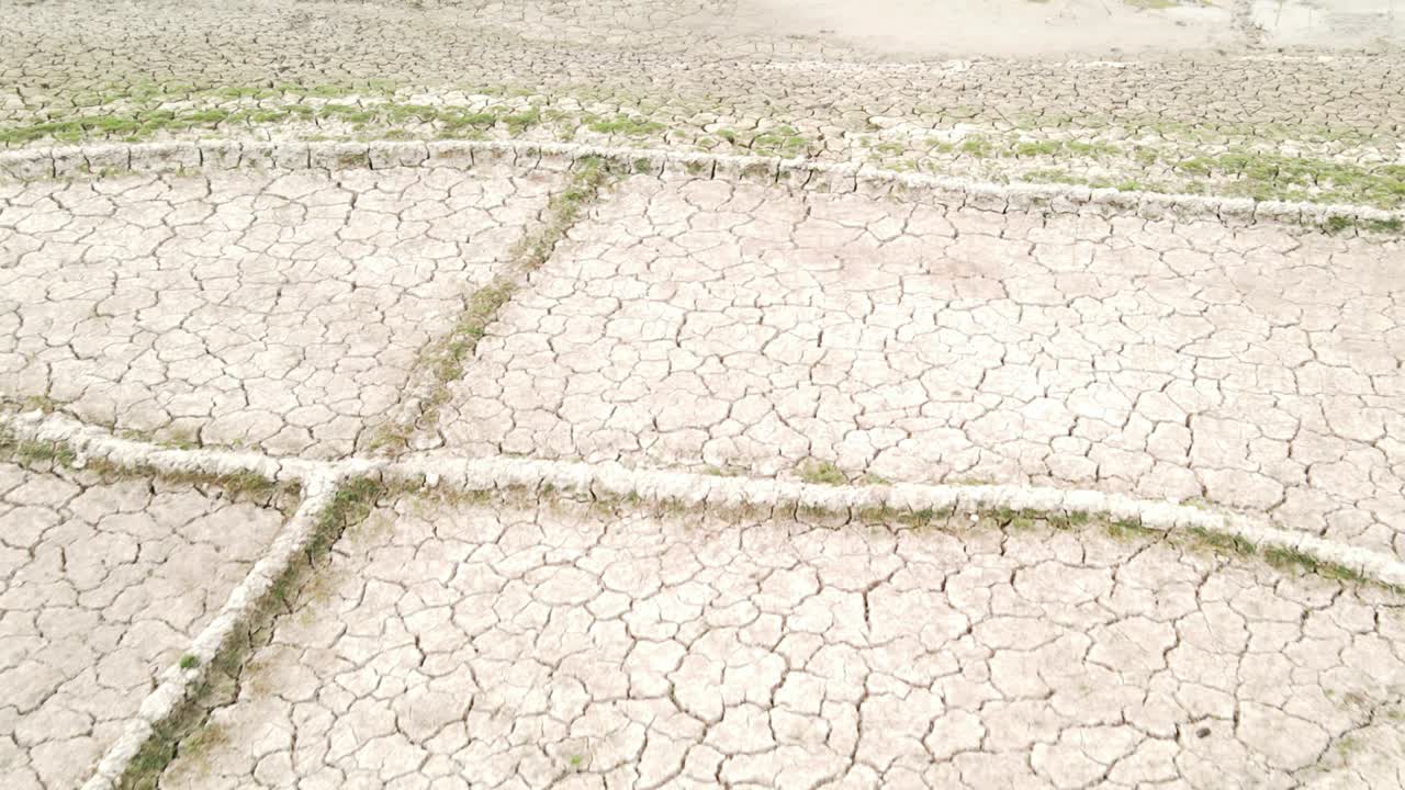 마른 연못의 항공 영상은 가뭄의 영향을 강조하는 관개 채널이 있는 불모의 농지를 보여줍니다.