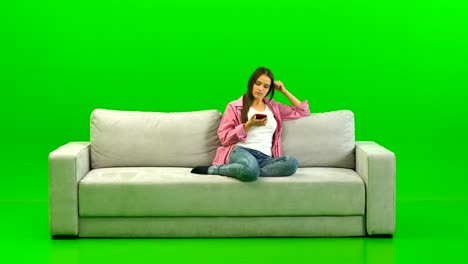 the woman phones on the sofa on the green background
