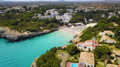 Cala-Anguila-Con-Aguas-Cristalinas,-Bañistas-Y-Villas-Circundantes,-Soleada-Vista-Aérea