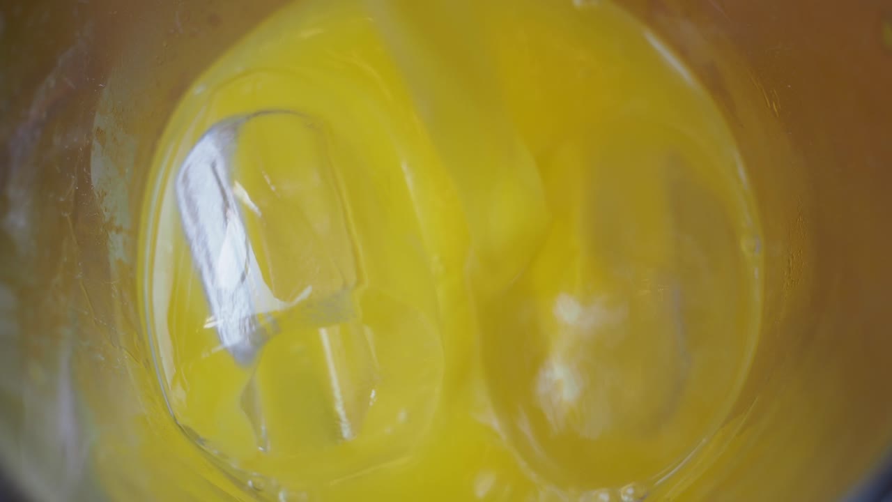 Pouring orange juice into a glass with ice cubes