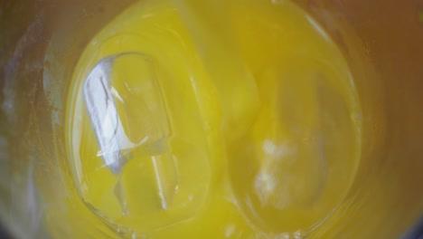 pouring orange juice into a glass with ice cubes