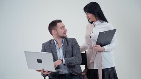 businessman and attractive secretary in studio. handsome man sitting with a laptop talking to a pretty woman. slow motion.