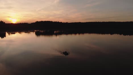 beautiful sunset and calmness of a lake with person paddling a rubber boat during summer evening in rogowko, poland