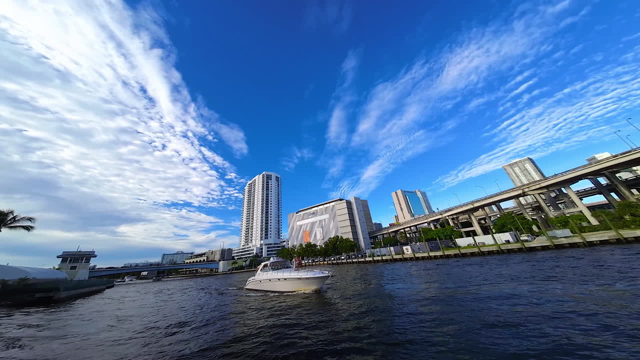 White modern motor boat moving by the channel in American city. FPV drone footage around the vehicle on water.