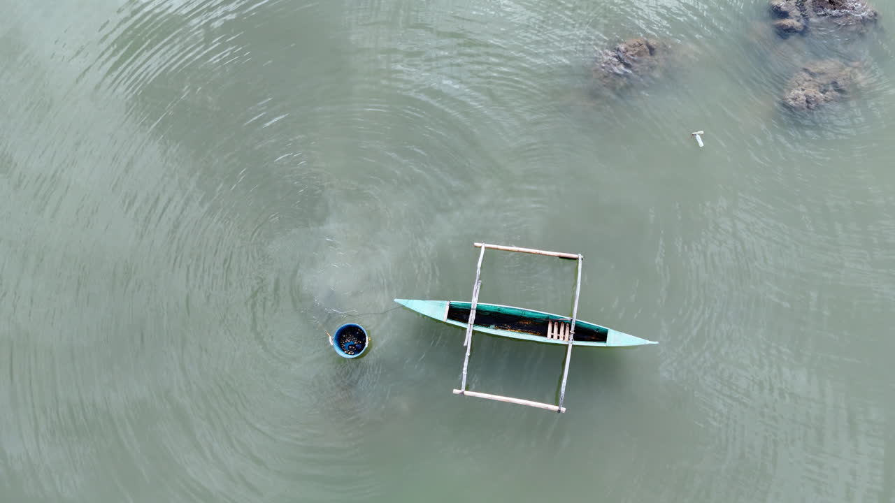 Bird eye static shot of a local fisherman harvesting clams in the shallow brackish waters of Inner Malampaya Sound during a calm day