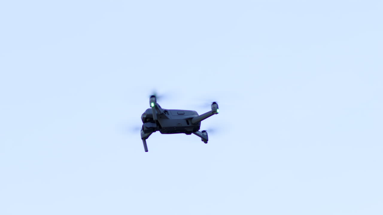 Grey drone flying and filming throughout the city