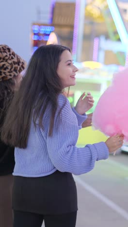 young women enjoying cotton candy at an amusement park