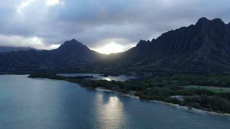 static aerial shot above a calm ocean fish pond with a large mountain range in the background