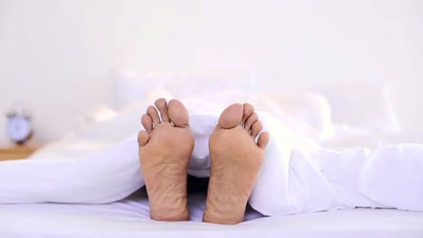 man wiggling his toes under the duvet