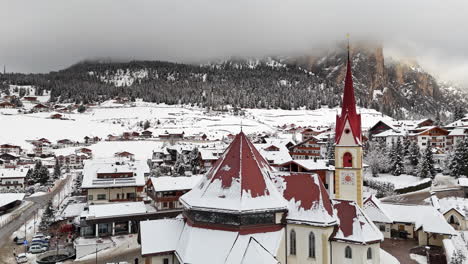 snowy town with church in selva di val gardena