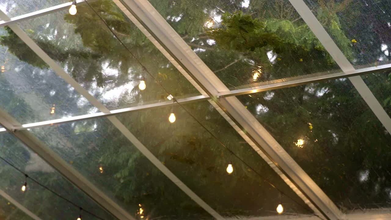bombillas conectadas a un cable en una tienda transparente, lluvia fuerte cayendo