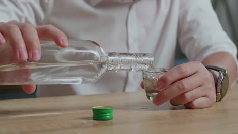 man pouring vodka into a shot glass