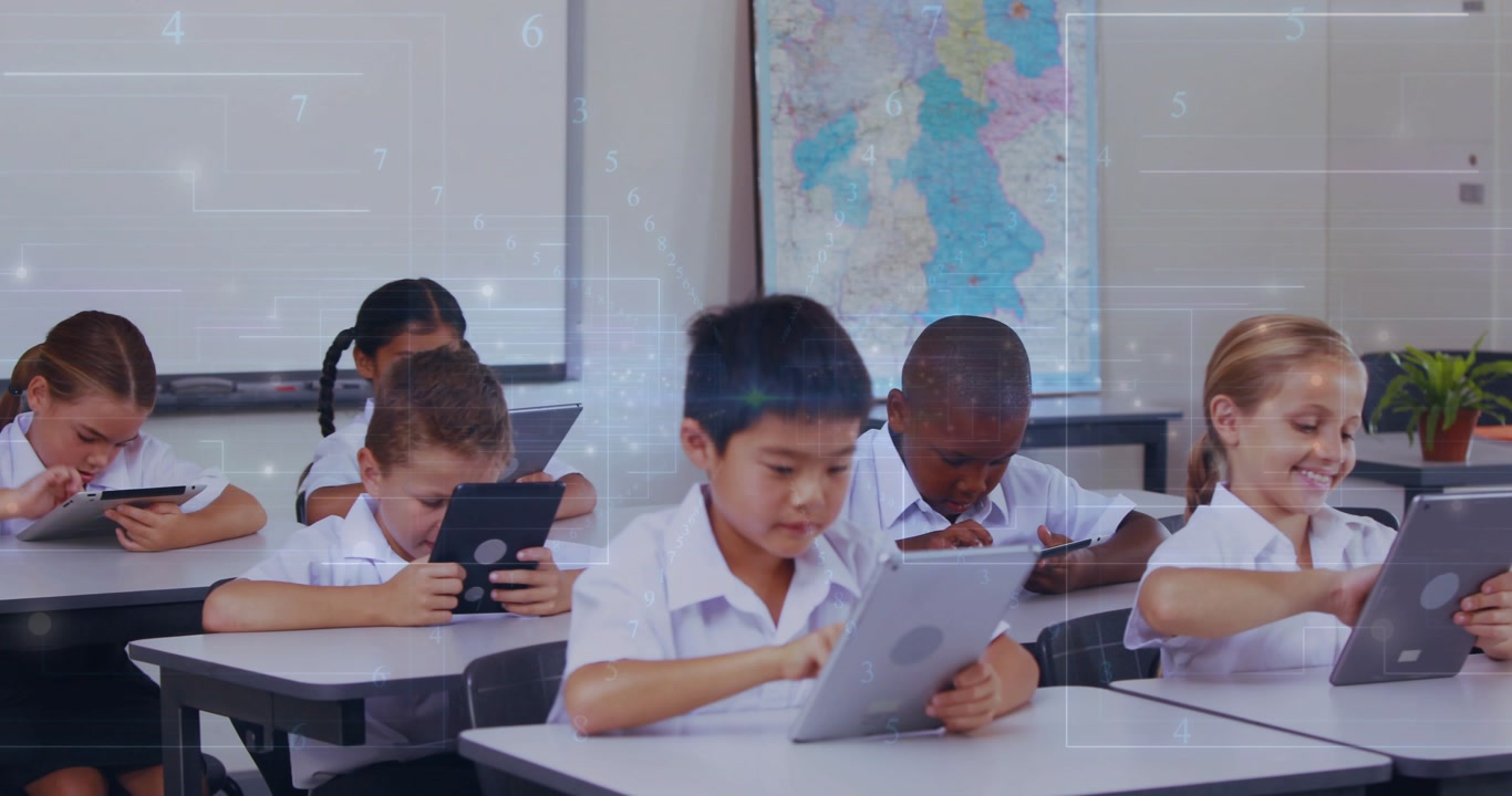 Teacher leaning over left desk and moving past rows, checking tablets and guiding school progress