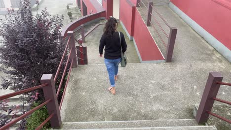 vista trasera de una joven india feliz vestida de negro caminando por las escaleras de un monasterio