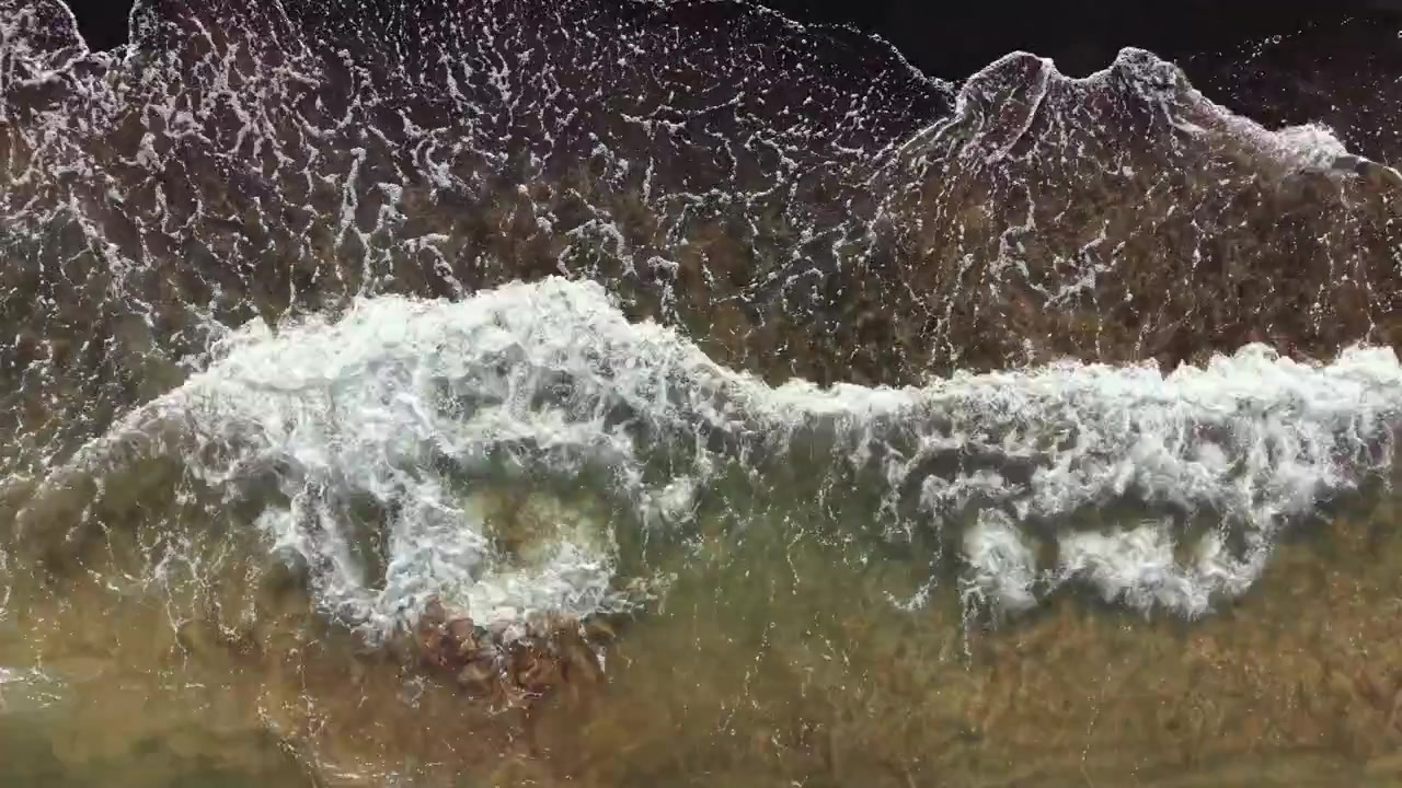 Waves crash on the shore as the tide rolls in during a sunny day at the beach near an ocean