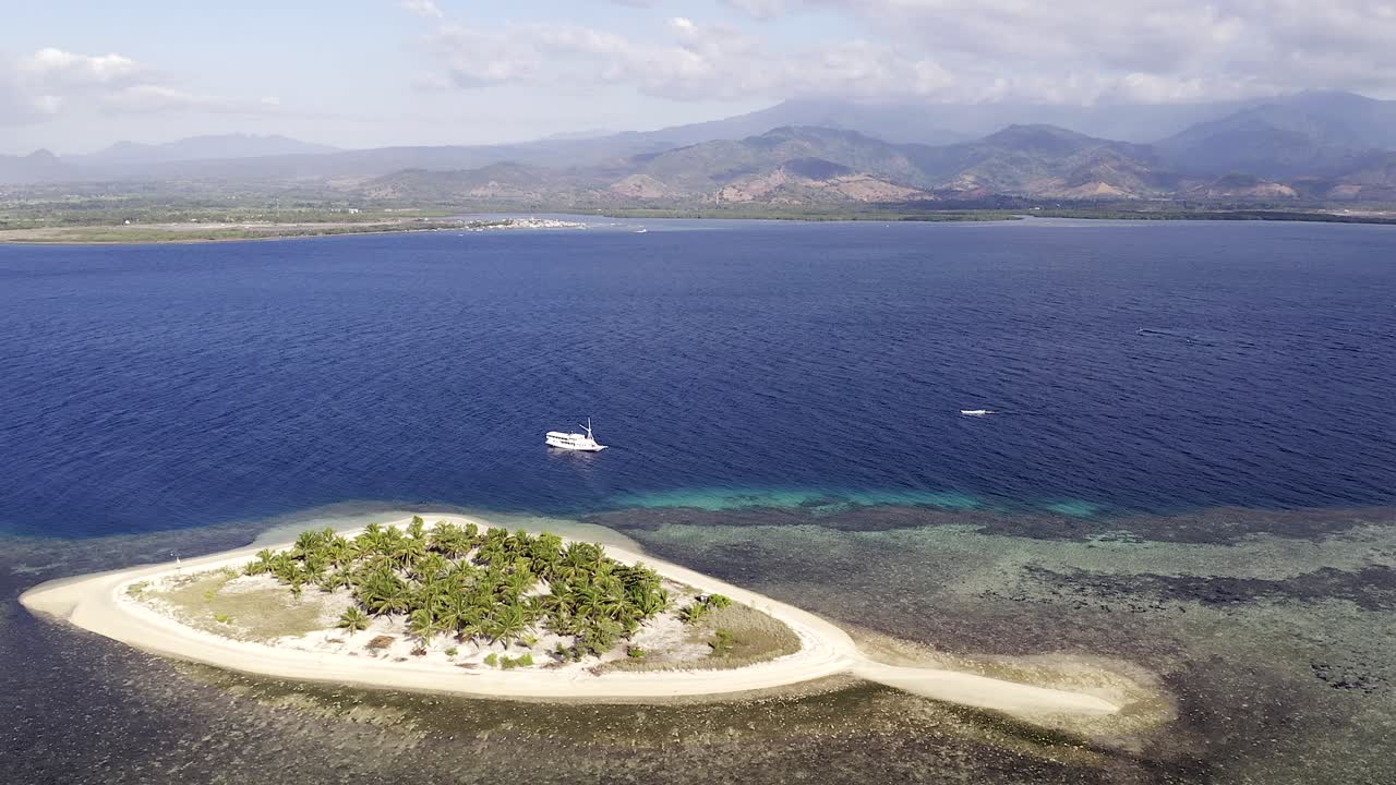 barco turístico anclado junto a pulau bedil, una pequeña y hermosa isla indonesia frente al escudo de lombok, vista aérea