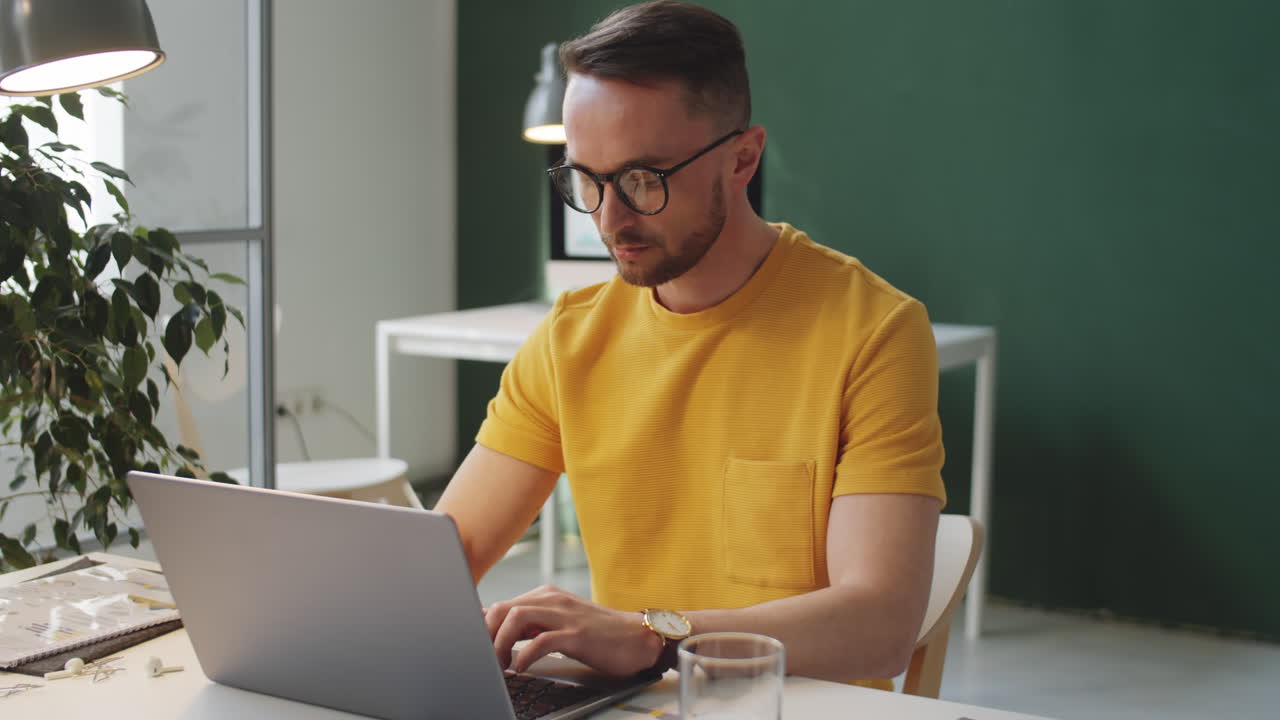 Caucasian Man Working on Laptop at Desk in Office