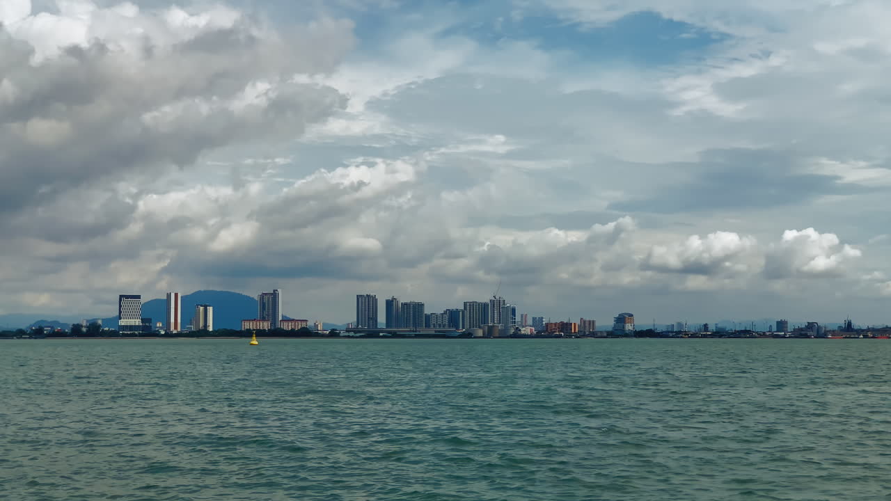 구름이 가득한 하늘 아래 평온한 물을 특징으로하는 도시 해안의 경치가 아름답습니다.