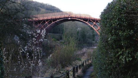 people walk over the first bridge made of cast iron in the town of ironbridge, england