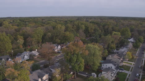 Tilt-down-over-suburban-neighborhood-in-Autumn-as-a-car-drives-down-the-street-and-pulls-into-a-driveway