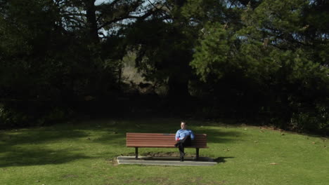 a man sits on a park bench alone with a flower