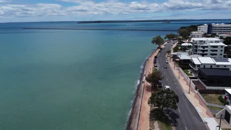 Drohne,-Die-An-Einem-Küstenort-Mit-Einem-Langen-Pier-Im-Hintergrund-Absteigt