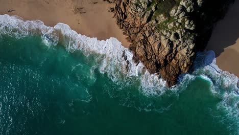 beautiful coastline ocean waves along rocky beach in cornwall, top down view