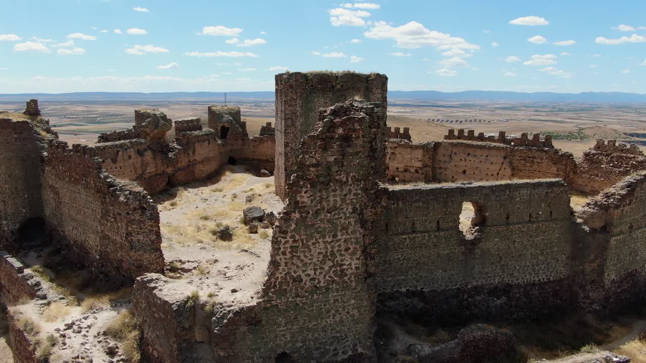 vuelo orbital con un dron sobre una fortaleza amurallada con sus torres y la fortaleza en el medio rodeada de campos de cultivo en un día de verano con un cielo azul con nubes en toledo españa