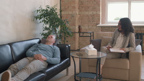 man lying on couch and talking to therapist