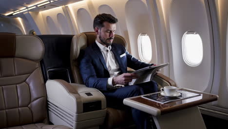 man reading newspaper in first class airplane seat