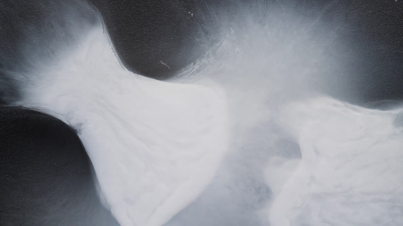 White alcoholic ink swirls in water, creating soft, abstract macro cloud shapes