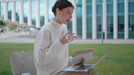 woman greeting friends online meeting using laptop outdoors close up. video chat