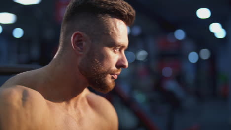 tired bodybuilder resting after training. young handsome athlete sitting and drinking water. close-up portrait of a sportsman.
