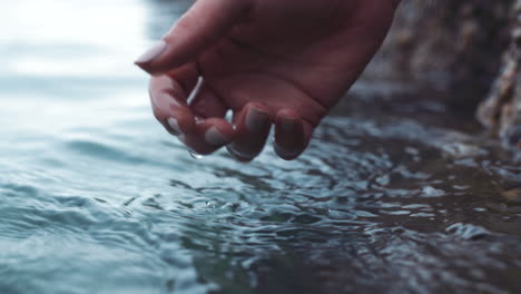 Woman,-hands,-and-touching-ocean-water-at-beach