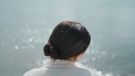 꿈꾸는 여자가 물 물결을 뒤로 바라보고 있습니다. 강 표면을 즐기는 어린 소녀.