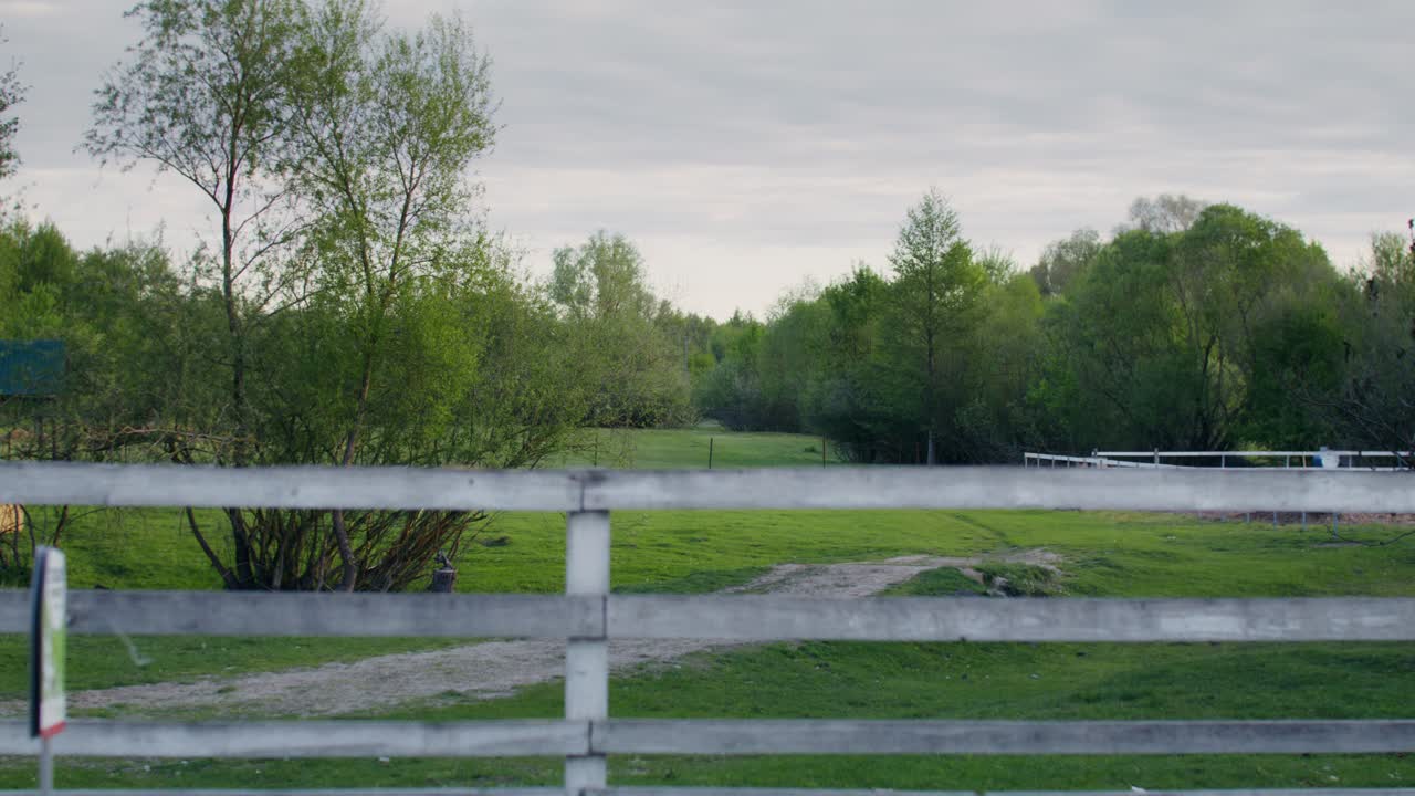 Countryside View Through a White Wooden Fence
