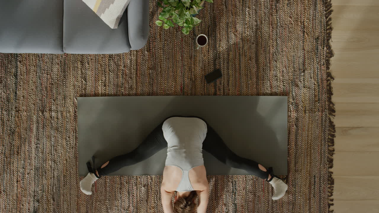 vista superior de una mujer de yoga practicando una postura de curvatura hacia adelante sentada en gran angular ejercitando un estilo de vida saludable en casa en una colchoneta de ejercicios disfrutando de la meditación de atención plena