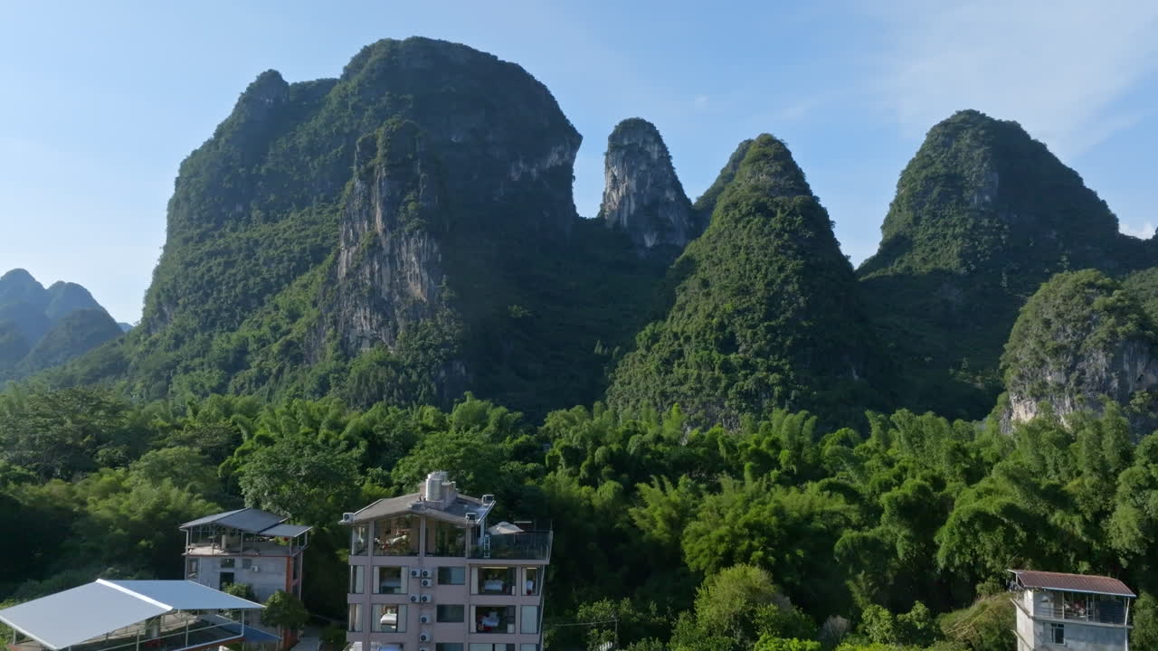Aerial ascending shot houses and the karst mountains in Xingping, sunny China