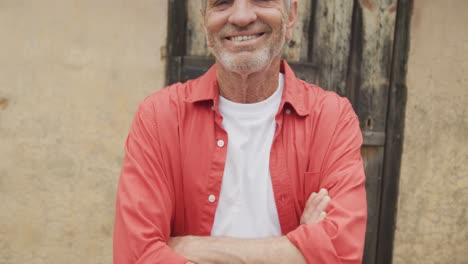 retrato de un hombre caucásico mayor sonriente con los brazos cruzados