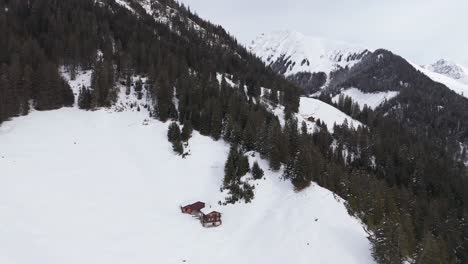 snowy alpine landscape with wooden cabins in langwies, switzerland, aerial view
