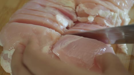 close-up of chicken breast being sliced on cutting board