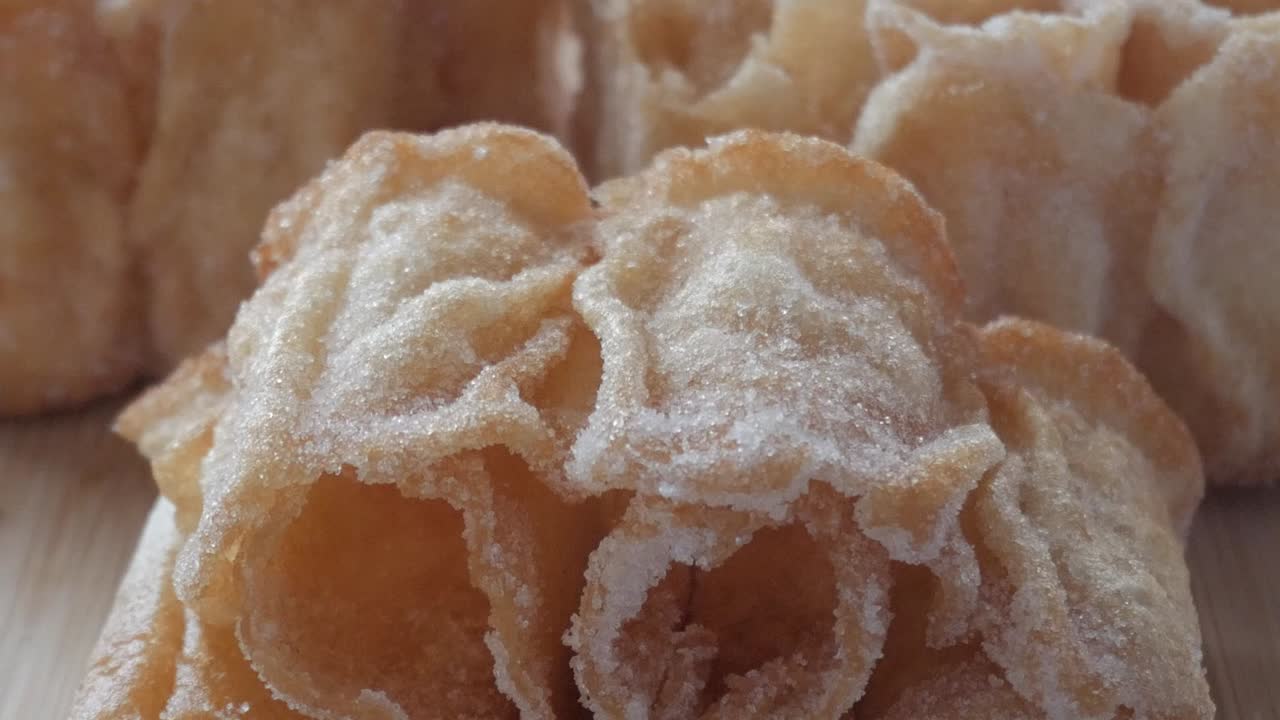 Close up shot of traditional Spanish sweet "flor frita" with sugar, crispy texture and elegant flower shape over wooden surface