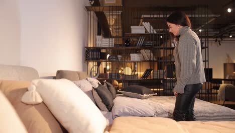 a young woman in a gray sweater chooses a blanket for a bed in a furniture and textile store a young woman in a gray sweater chooses a blanket for a bed in a furniture and textile store high quality footage