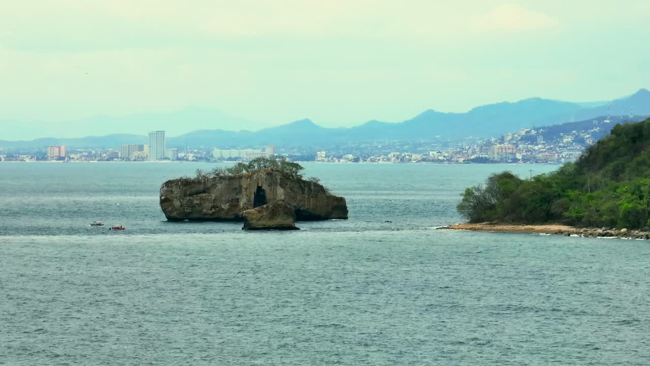 Static aerial view of Los Arcos rock islets and beach in Mismaloya, with Puerto Vallarta city in the background, Mexico