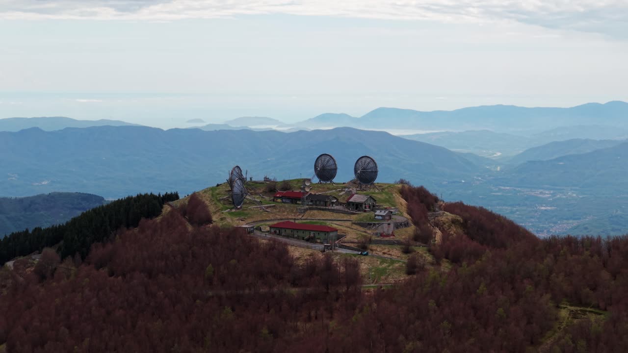 Old radar station with large dishes on mountain peak, aerial view, calm and remote