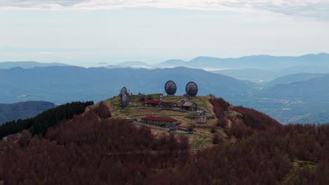 old radar station with large dishes on mountain peak, aerial view, calm and remote