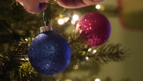 cerca de una persona que decora un árbol de navidad con adornos brillantes