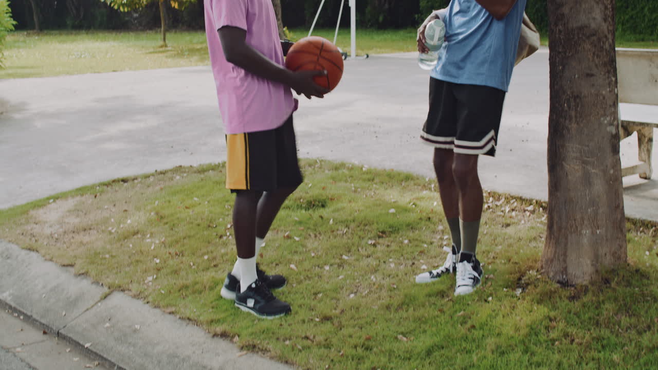 African American Guys Chatting on Basketball Court Outdoors